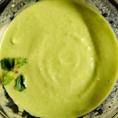 a glass bowl filled with green liquid and garnished with leaves