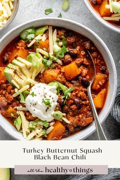 two bowls filled with turkey, butternut squash and black bean chili next to an avocado