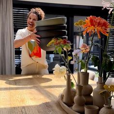 a woman sitting at a table with vases and flowers