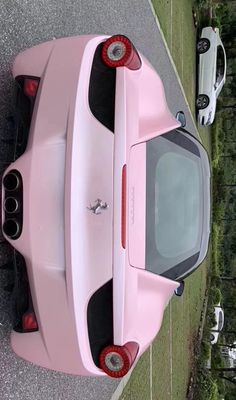 the back end of a pink sports car parked in a parking lot next to other cars