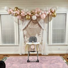 a baby's first birthday party setup with balloons and pink, gold and white decorations