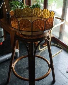 a stained glass flower pot sitting on top of a wooden table next to a window