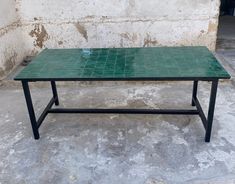 a green table sitting on top of a cement floor