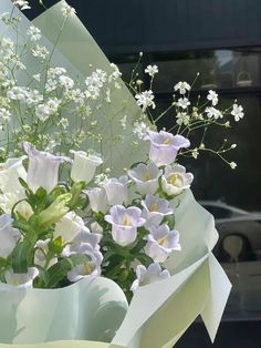 a bouquet of white and purple flowers in front of a car