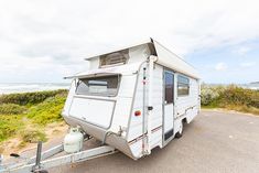 an rv is parked on the side of the road by the beach and water in front of it