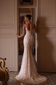 a woman in a wedding dress is standing near a doorway and looking at the mirror