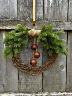 a wreath with pine cones and acorns hanging on a wooden door, ready to be used as an ornament