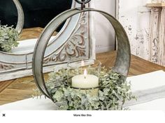 a candle that is sitting in a vase on a table with a mirror behind it