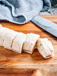 a sliced up tortilla sitting on top of a wooden cutting board next to a knife