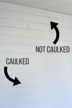 two black arrows pointing in opposite directions on a white painted wall that says not caulked