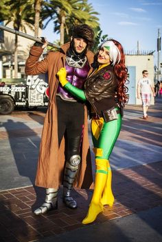 two people dressed in costumes standing next to each other on a sidewalk with palm trees behind them