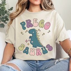 a woman sitting on a couch wearing a t - shirt that says rego and dinosaurs