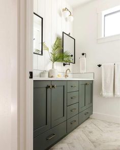 a bathroom with green cabinets and white walls