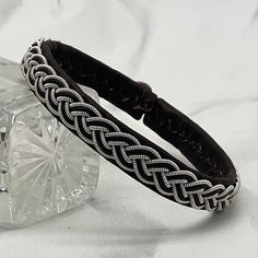 a black leather bracelet sitting on top of a crystal block next to a glass object