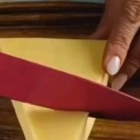 a person is cutting paper with a pair of scissors on top of the piece of yellow paper