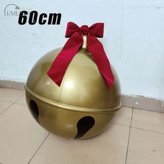 a large metal ball with a red bow on it's top sitting on the floor