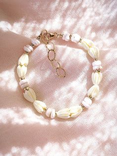 Flanked with natural white puka shells and pikake flowers, this unique shell bracelet evokes visions of Hawaii's white sands and soothing shores. Stack this gold bracelet with other beaded beauties and you'll be ready for your tropical escape.✦ DETAILS ✦✧ Name: Me'e (MAY aye) - Heroine.✧ Adjustable from 6.5"-8".✧ 6-7mm White Puka Shells.✧ Carved Resin Pikake Flowers.✧ 14kt Gold Filled with lobster clasp.✧ All Ke Aloha Jewelry pieces come packaged thoughtfully, beautifully, and ready for gift giv Handmade White Pearl Bracelet For Vacation, White Bohemian Beaded Shell Bracelets, White Adjustable Shell Necklace Spiritual Style, White Adjustable Shell Necklace For Spiritual Wear, Dainty White Shell Necklace, White Adjustable Spiritual Shell Necklace, White Hand-strung Bracelets For Vacation, White Hand-strung Bracelet For Vacation, Hand-strung White Bracelets For Vacation