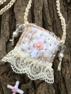 a small purse hanging from a tree with beads and pearls on the bottom of it