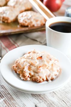 a white plate topped with cookies covered in icing next to a cup of coffee