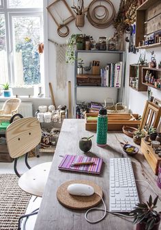 a desk with a keyboard, mouse and other items on it in a room filled with plants