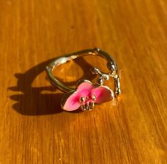 a pink flower ring sitting on top of a wooden table