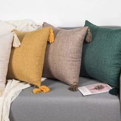 four different colored pillows on a gray couch