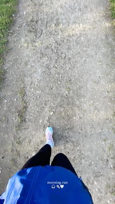 a person with their feet in the air on a dirt road next to grass and trees