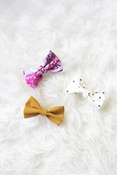 three small bow ties laying on top of a white fur covered floor next to each other