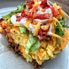 a slice of taco salad on a plate with sour cream sauce and lettuce