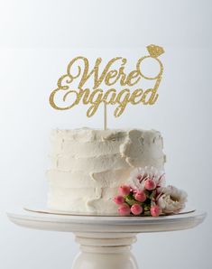 a white cake with gold lettering and flowers on top