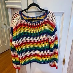 a colorful crocheted sweater hanging on a door