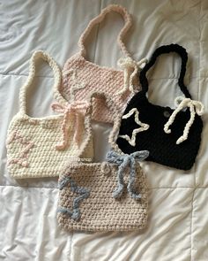 four crocheted purses sitting on top of a white bed next to each other