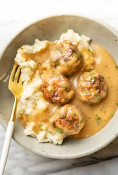 a bowl filled with meatballs and gravy on top of mashed potatoes