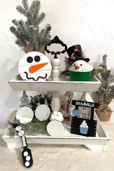 three tiered shelf with snowman decorations and other holiday items on it's sides