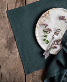 a white plate topped with flowers next to a fork and knife on top of a green napkin