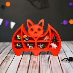 an orange bat shaped toy on top of a wooden table next to halloween candies