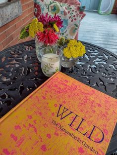 a book sitting on top of a table next to a vase with flowers in it