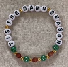 a beaded bracelet with beads and charms on it that says,'the damn season '