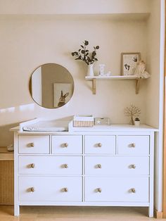 there is a white dresser with drawers and a mirror on the wall next to it