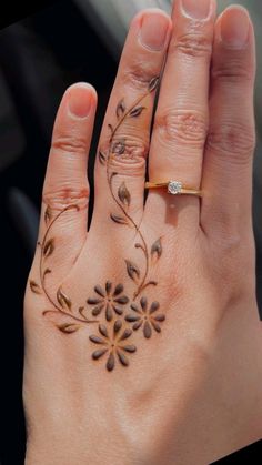 a woman's hand with a ring on it and flowers painted on the palm