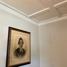 an old photo hangs on the wall above a bench in a room with white walls