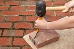 a person is holding an hammer over a block of bricks