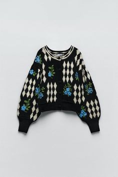 a black and white sweater with blue flowers on it