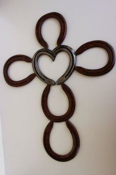 a cross made out of horseshoes on top of a white wall with a heart cut in the middle