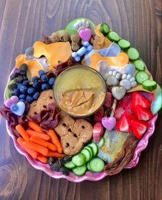 a platter filled with fruit, veggies and crackers on top of a wooden table