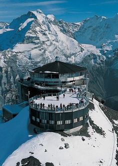 a building on top of a snowy mountain with mountains in the background