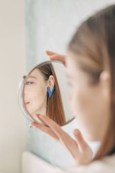 a woman is looking at her reflection in the mirror while she brushes her long hair