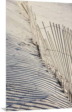 a fence and sand on the beach that is covered in snow, with grass growing out of it