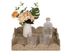 a vase with flowers and two empty glasses on a wicker tray, isolated against a white background