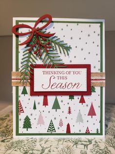 a christmas card that says thinking of you this season with trees and bows on it